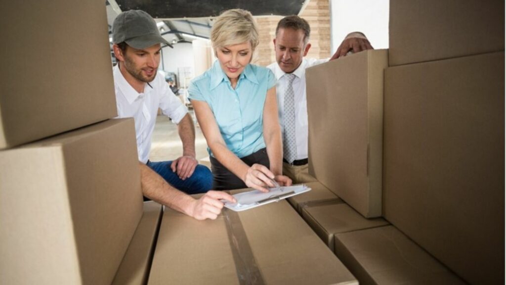 Warehouse team working together, reviewing inventory on a clipboard, with a focus on the staff members in the warehouse environment.